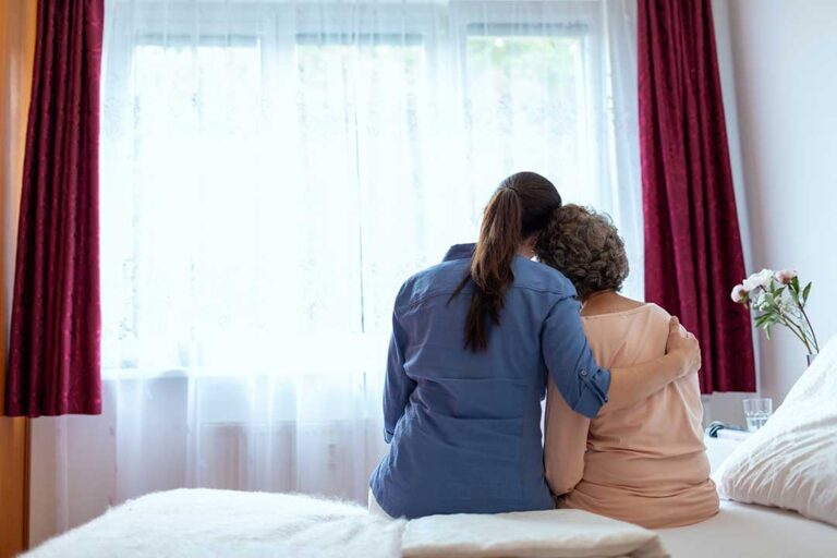 Social worker speaking with an assisted living resident and family member at a table with care notes.