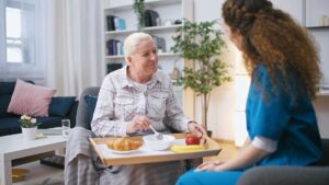 Family member sits beside an elderly resident in an assisted living room during a quiet care discussion.