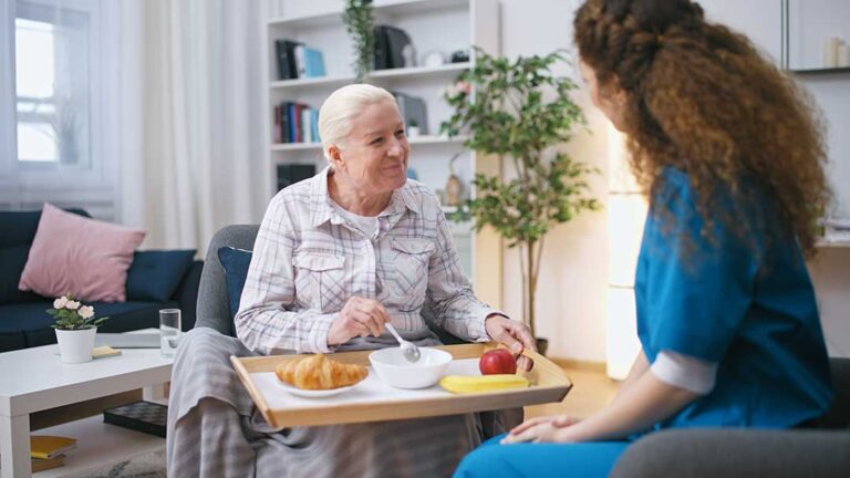 Family member sits beside an elderly resident in an assisted living room during a quiet care discussion.
